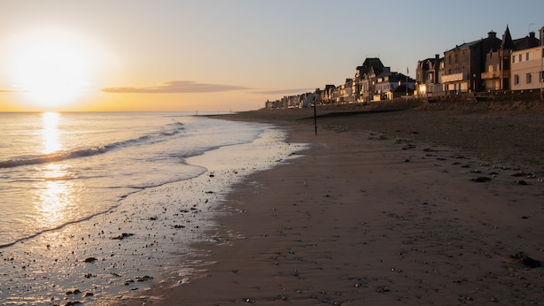 Une plage bordée d’une rangée de bâtiments.
