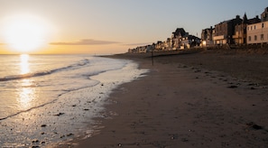A beach with a row of buildings along the shore. - Hotel Saint Aubin (Saint-Aubin-sur-Mer)