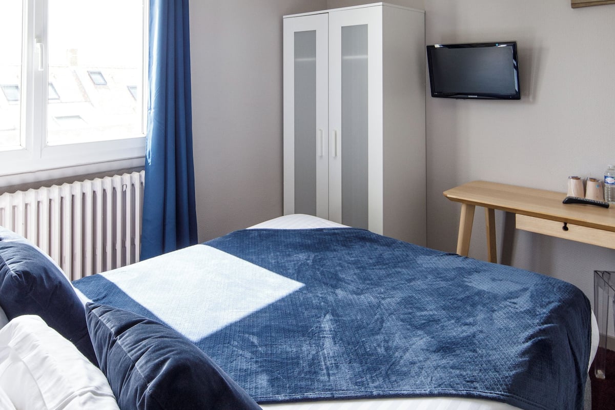 Een hotelkamer met een bed, bureau, televisie en kledingkast.