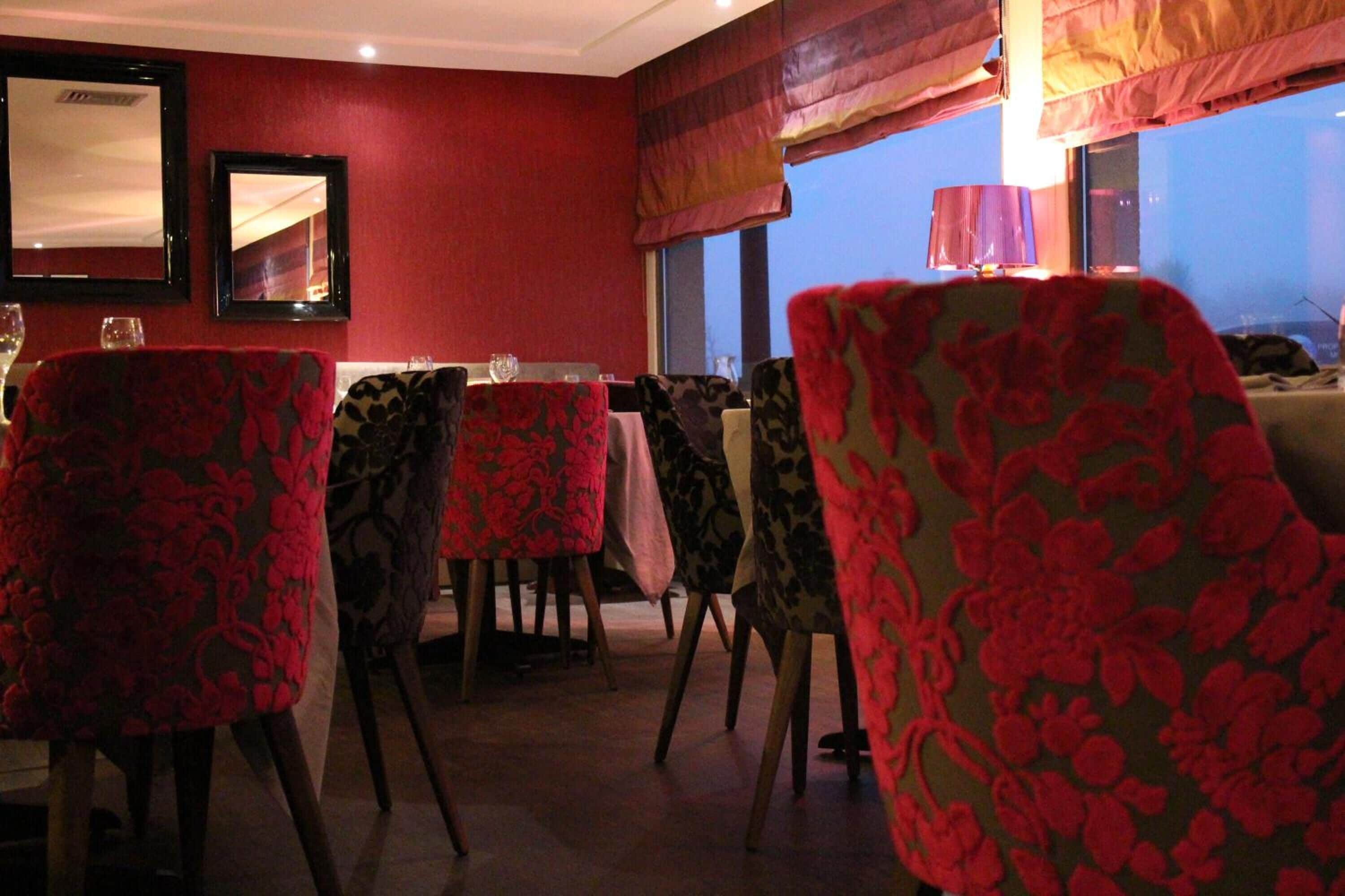 A dining area with red walls, patterned chairs, and a table set for dining.