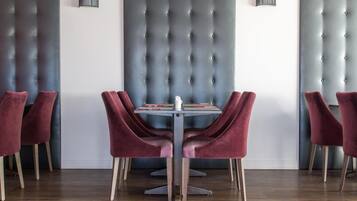 Un comedor con cabecera tapizada, una mesa redonda y seis sillas de terciopelo.
