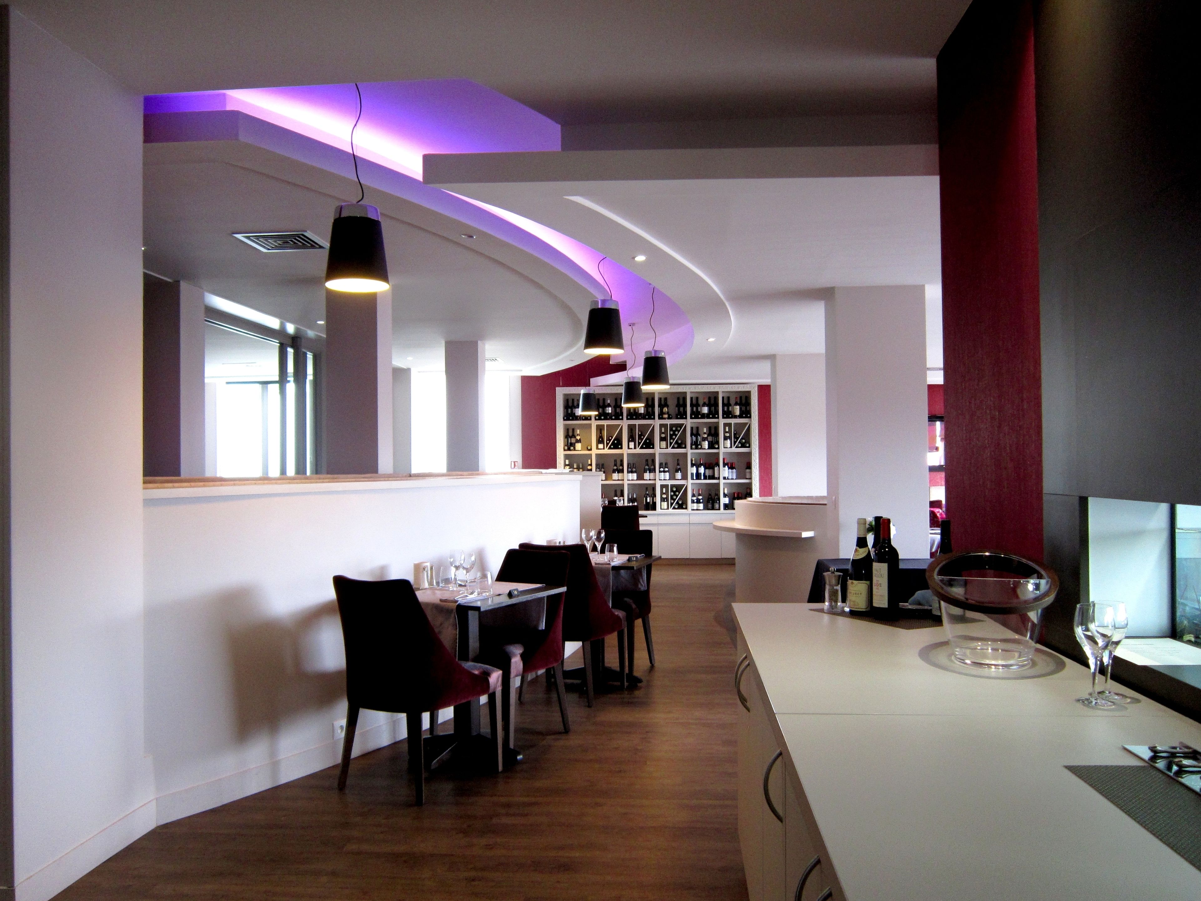 A modern restaurant interior with a bar area, wooden flooring, and a wine display.