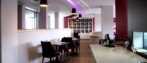 A modern restaurant interior with a bar area, wooden flooring, and a wine display.