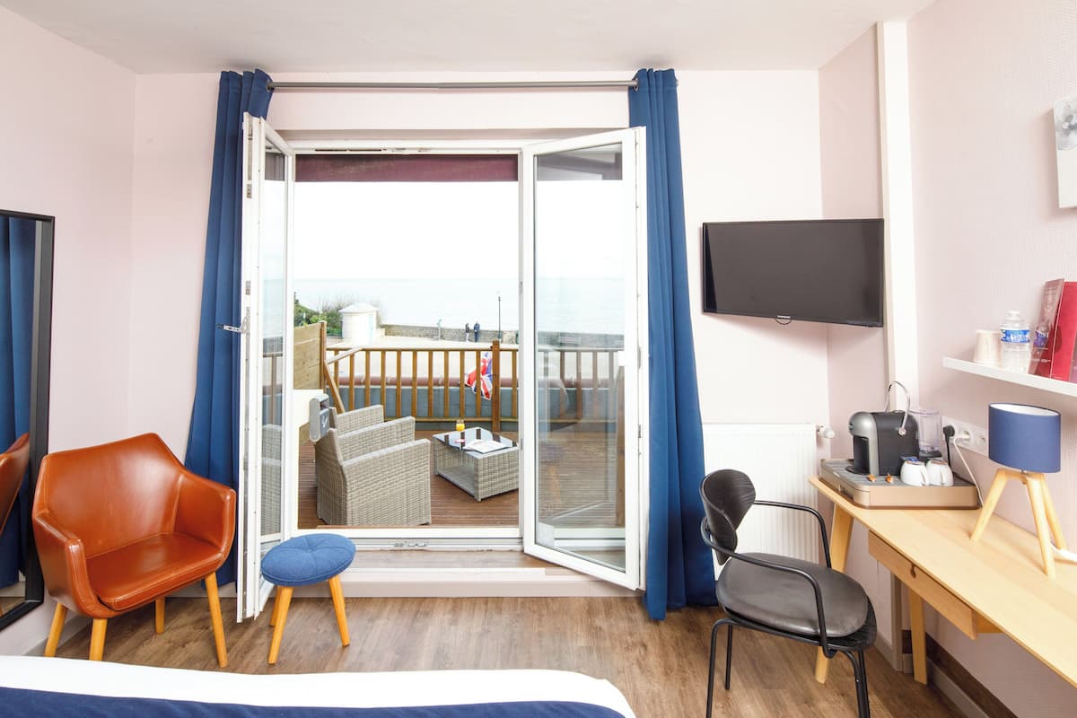 Een hotelkamer met balkon, bureau met computer, stoel en bed.