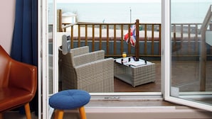 Un balcon agrémenté de meubles en osier, une table avec une boisson et une vue sur la mer.