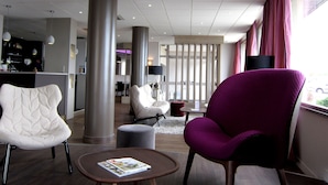 Un hall d’hôtel moderne doté d’un espace salon, d’un bar et offrant une vue sur l’extérieur.