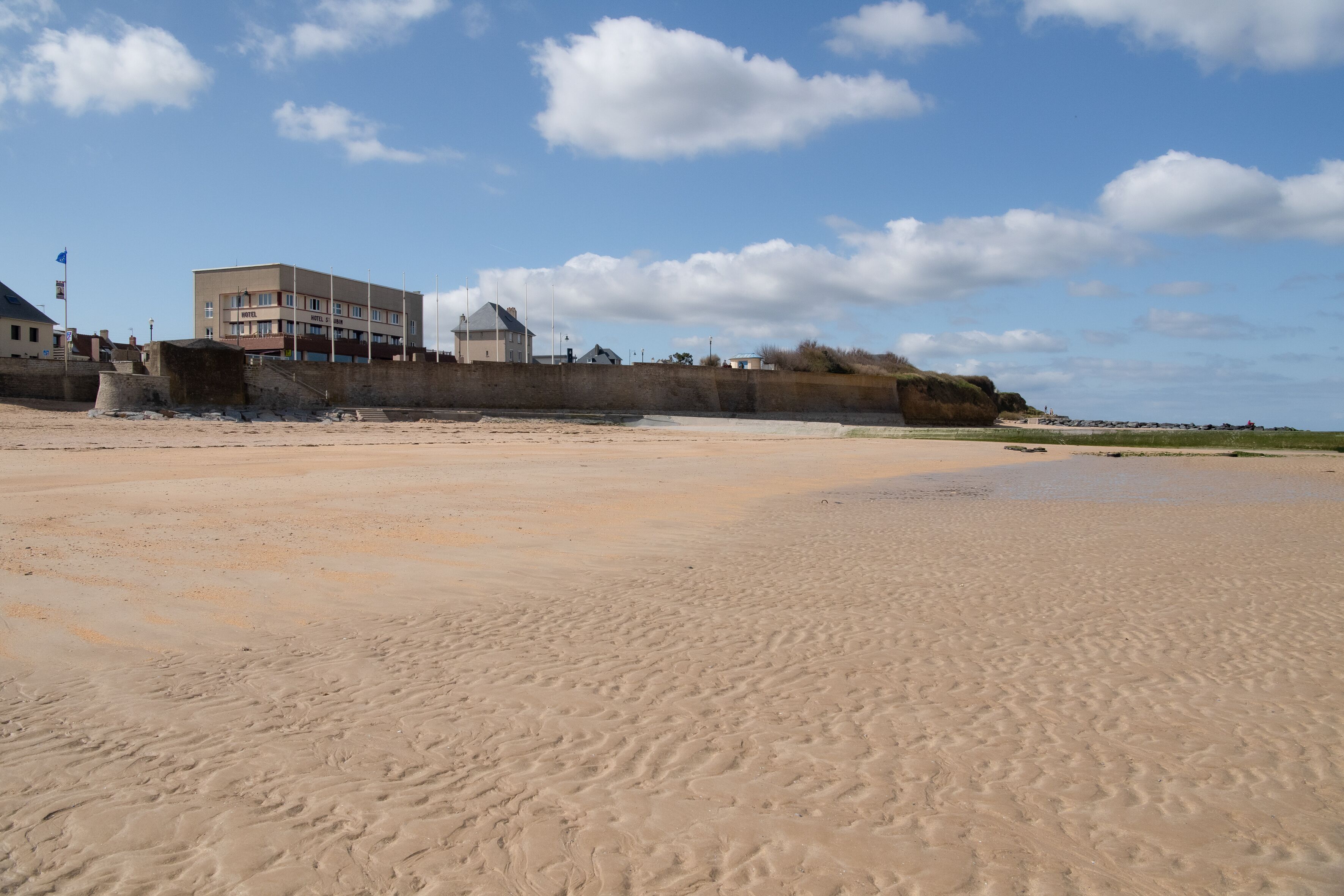 A sandy beach with a building in the background.