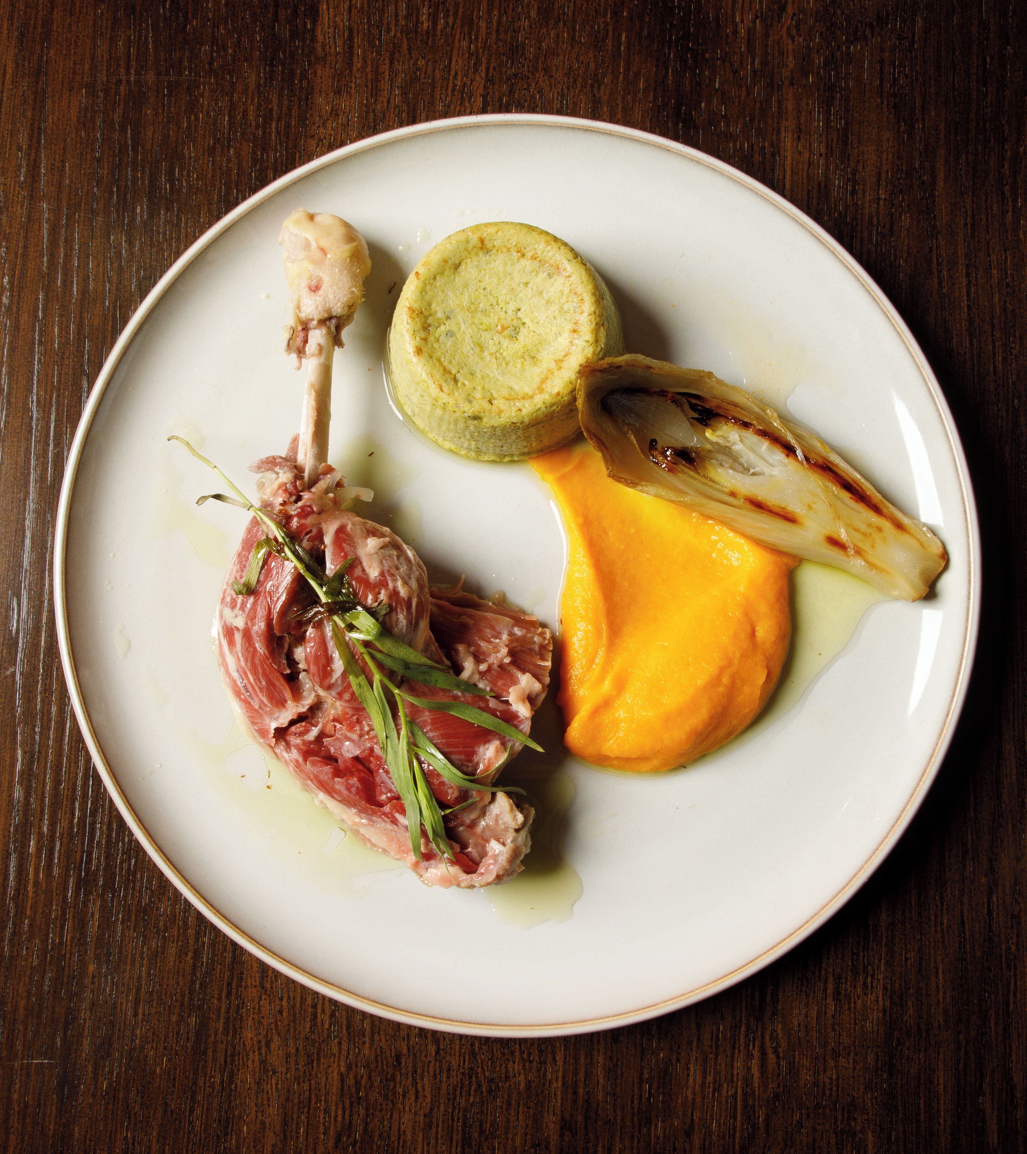 A plate with a piece of meat, a slice of bread, and a grilled vegetable.