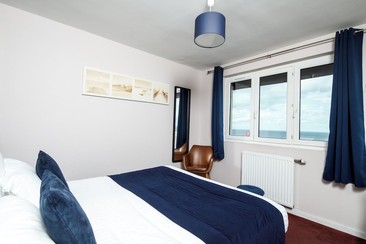 Een hotelkamer met een bed, een stoel, een raam met gordijnen en een plafondlamp.