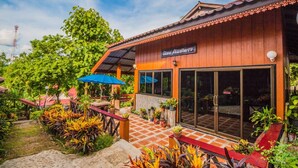 A wooden building with a tiled entrance and a covered patio area with outdoor seating.