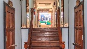 A wooden staircase with a handrail leading to a bright room with a green couch.