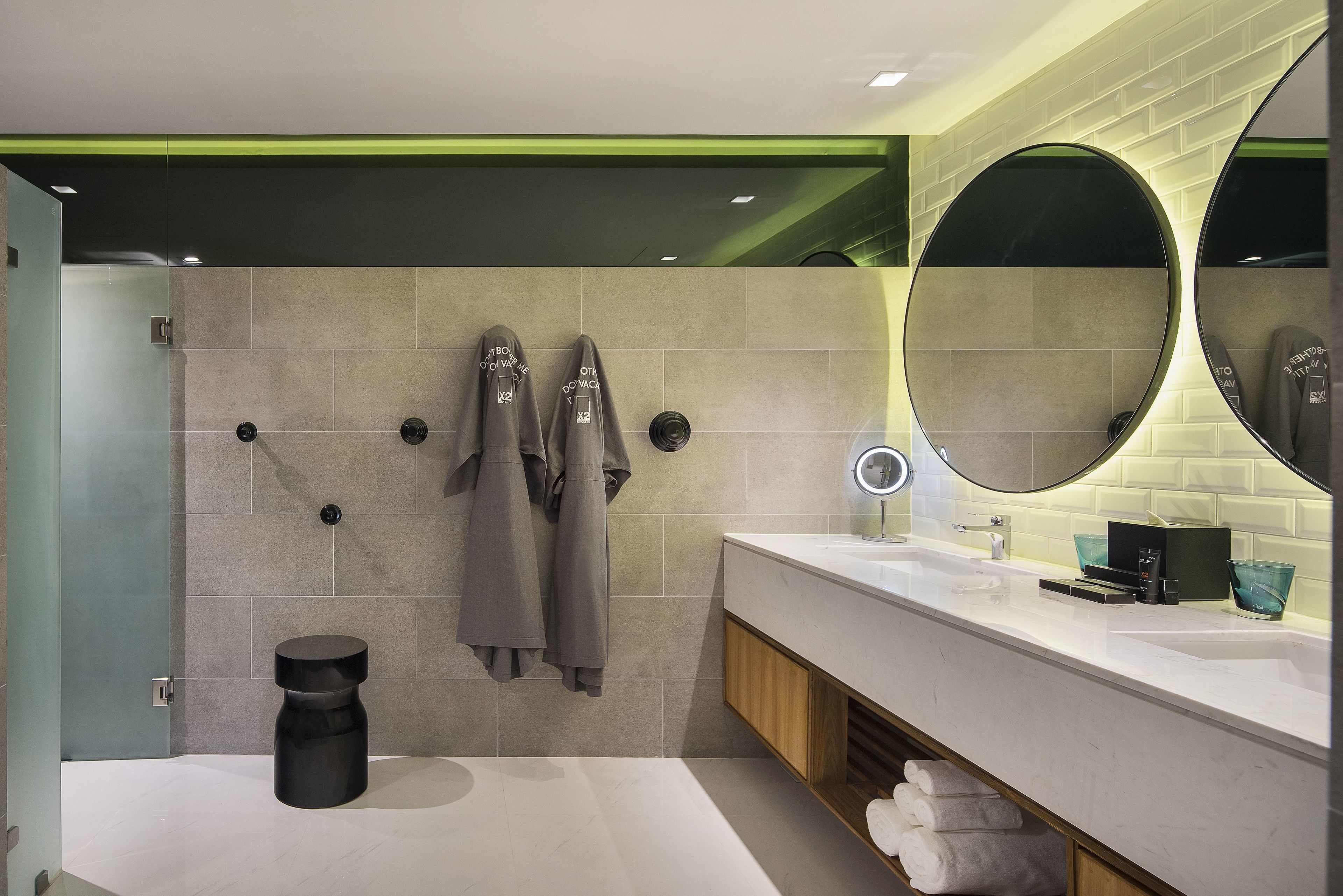 A modern bathroom with a large mirror, a sink, and a shower area.