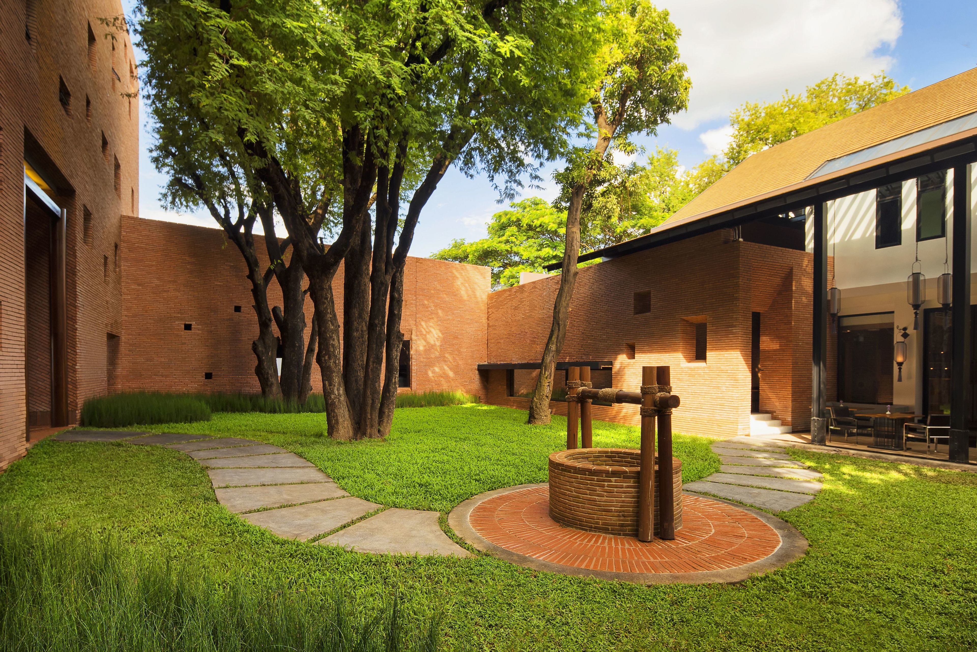 A courtyard with a brick building, a circular brick structure, and a pathway.