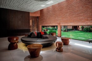 A modern interior with a circular seating area, a brick wall, and a view of a garden. - Cross Chiang Mai Riverside (Chiang Mai)