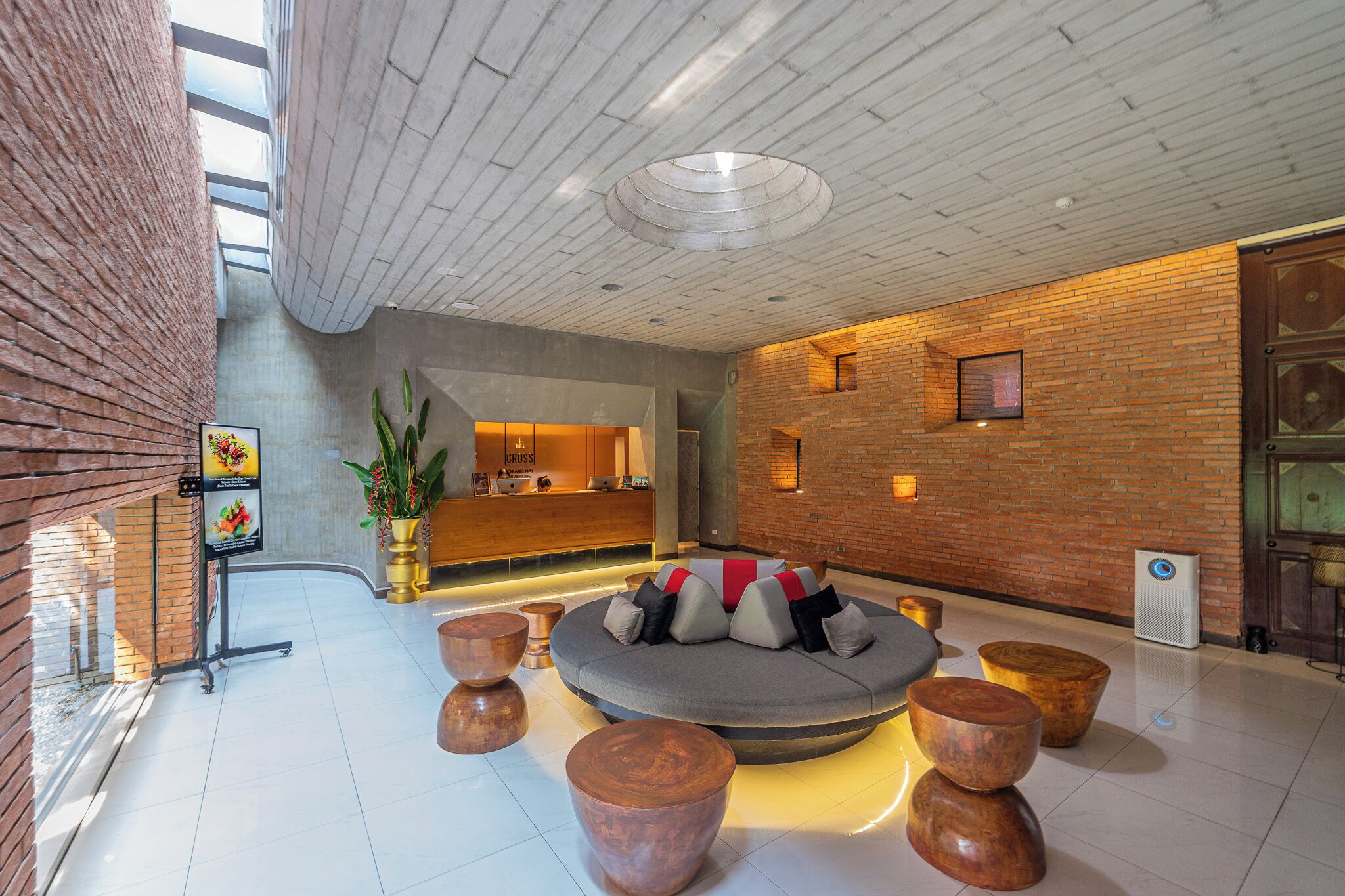Eine moderne Lobby mit Empfangstresen, Sitzgelegenheiten und einer großen Pflanze.