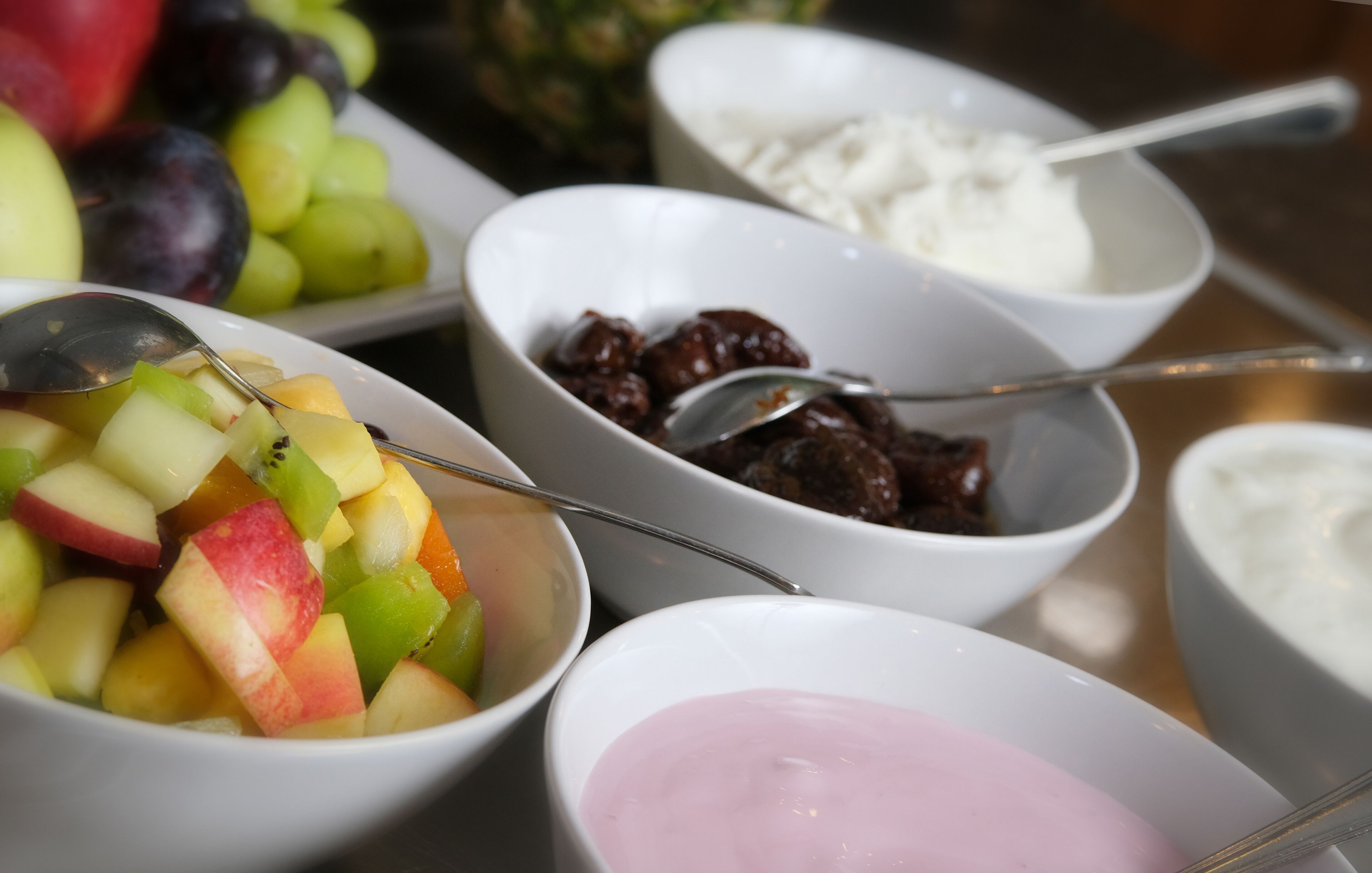 A variety of food items including fruits, yogurt, and a bowl of what appears to be a dessert or sweet dish.