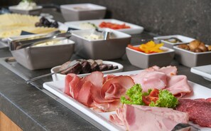 A buffet with various food items including meats, cheeses, and vegetables.