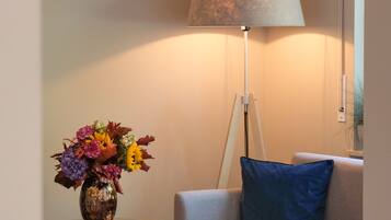 A room with a lamp, a vase of flowers, and a couch.