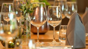A dining table set with wine glasses, a vase with flowers, and a napkin.