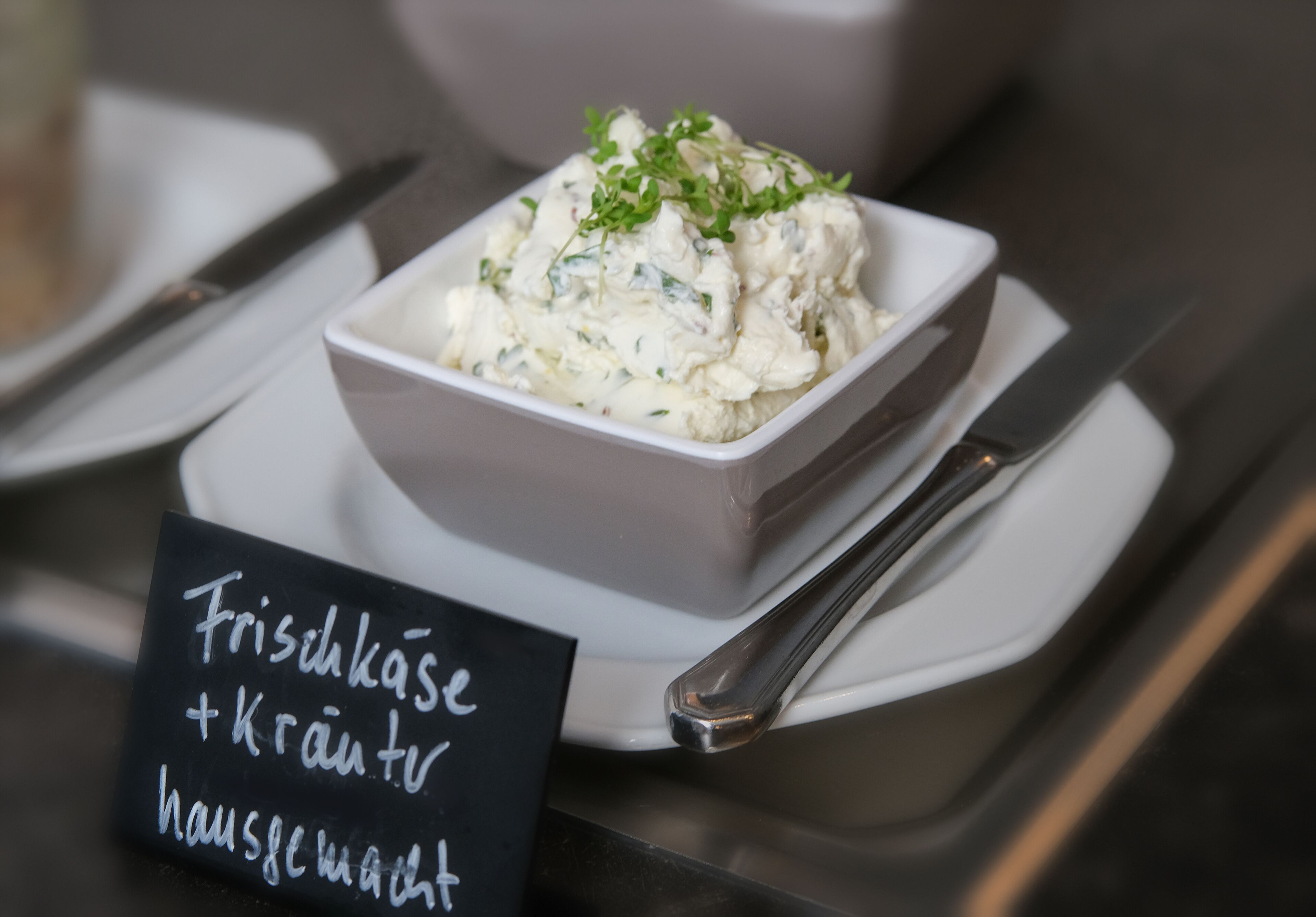 Un tazón blanco con ensalada, con un letrero que indica que es una ensalada fresca con arándanos y aderezo casero.