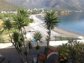 Vista costera con playa, un bote y un pueblo al fondo.