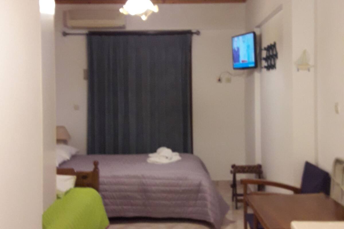 A small, cozy room with a bed, a desk, a chair, and a television.