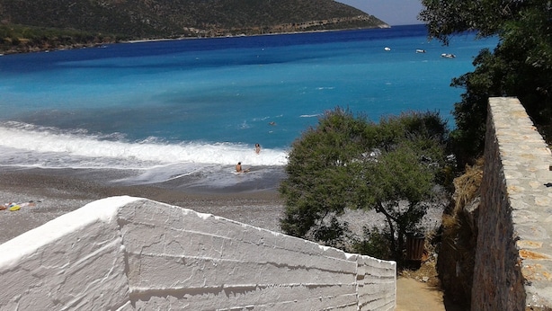 A stone pathway leading to a beach with clear blue water and a view of the sea. - Myrtoo (Monemvasia)
