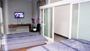 A bedroom with two beds, a TV, a desk, and a sliding door closet. - Setra Priangan Guesthouse (Bandung)