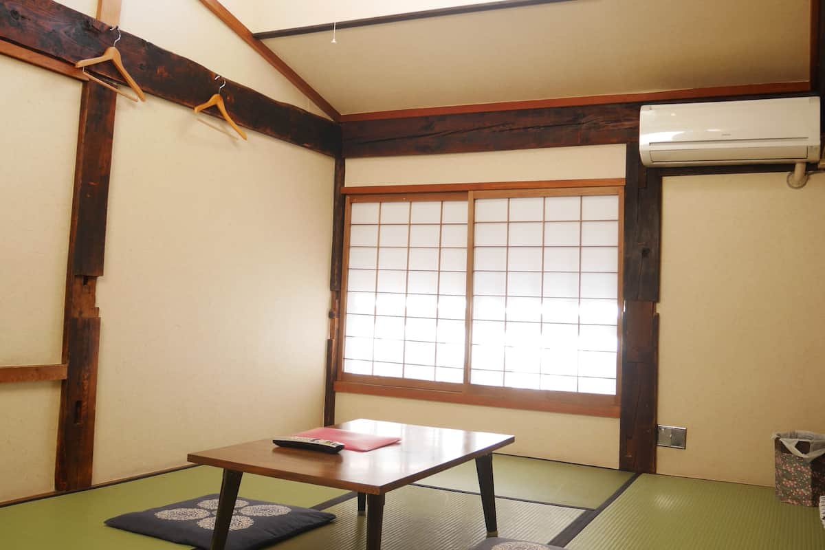 A tatami mat room with a low table, a hanging light fixture, and a sliding shoji screen door.