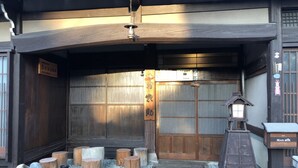 A traditional Japanese entrance with a wooden gate, stone steps, and a lantern. - Sosuke (Takayama)