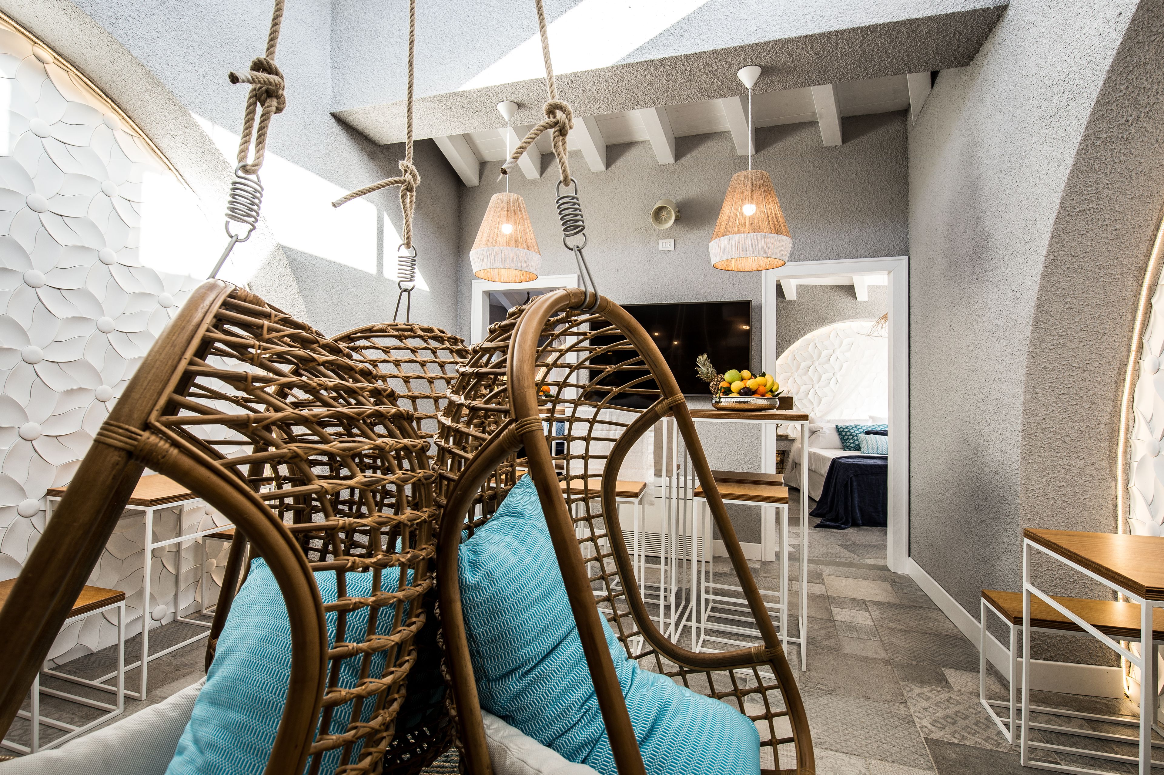 A modern interior with a hanging chair, a dining area, and a kitchen visible in the background.