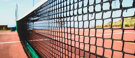 A tennis court with a net in the foreground.