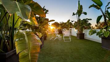 Un jardín en la azotea con césped artificial, plantas en macetas y mobiliario de exterior.