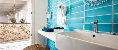 A bathroom with a white bathtub, a blue tiled wall, a white sink, and a mirror with a decorative frame.