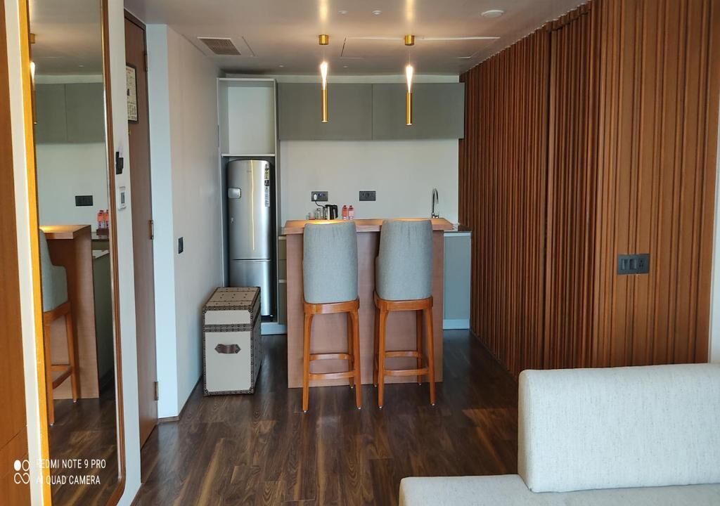 Una cocina moderna con refrigerador, dos taburetes de bar y una pared de acento de madera.