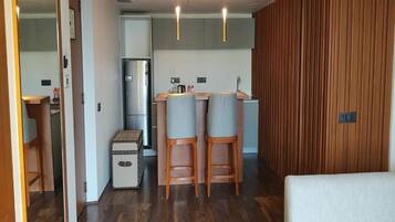 Una cocina moderna con refrigerador, dos taburetes de bar y una pared de acento de madera.