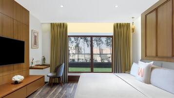 Habitación de hotel moderna con una cama grande, televisión, escritorio y vistas al exterior.