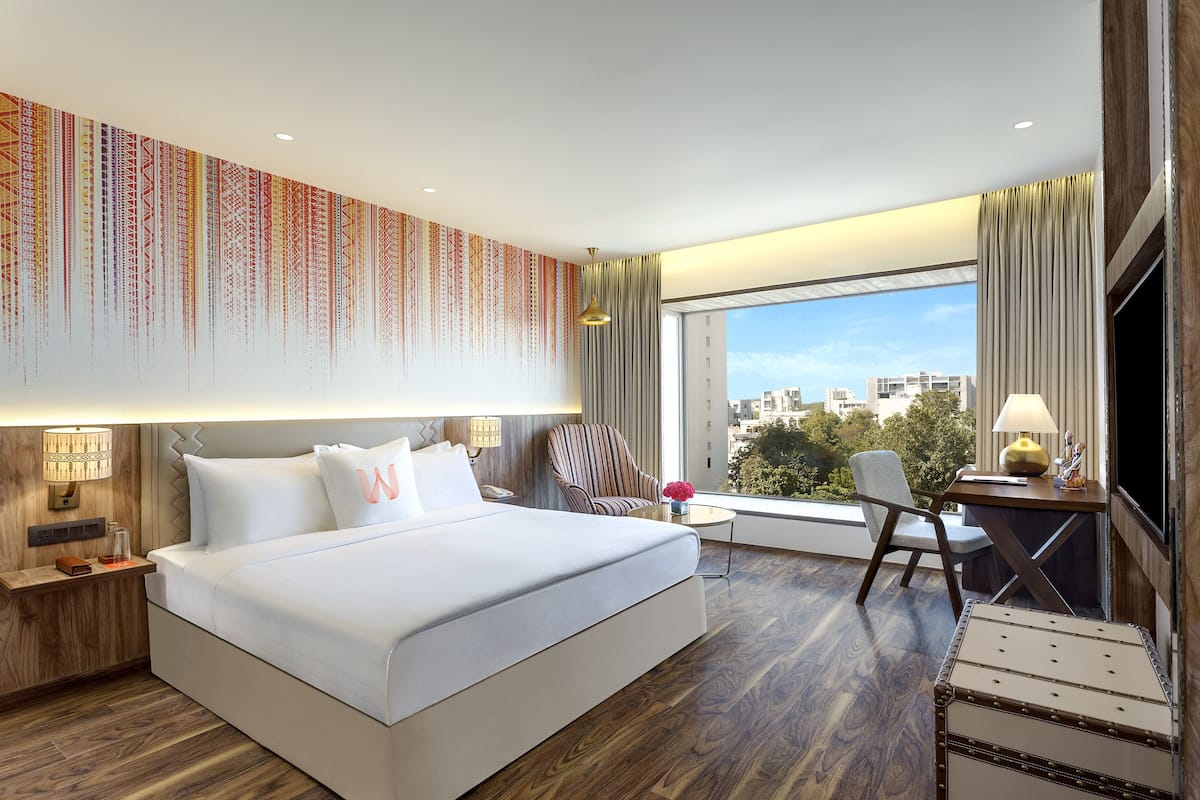 Habitación de hotel moderna con una cama grande, un escritorio y vistas de la ciudad.