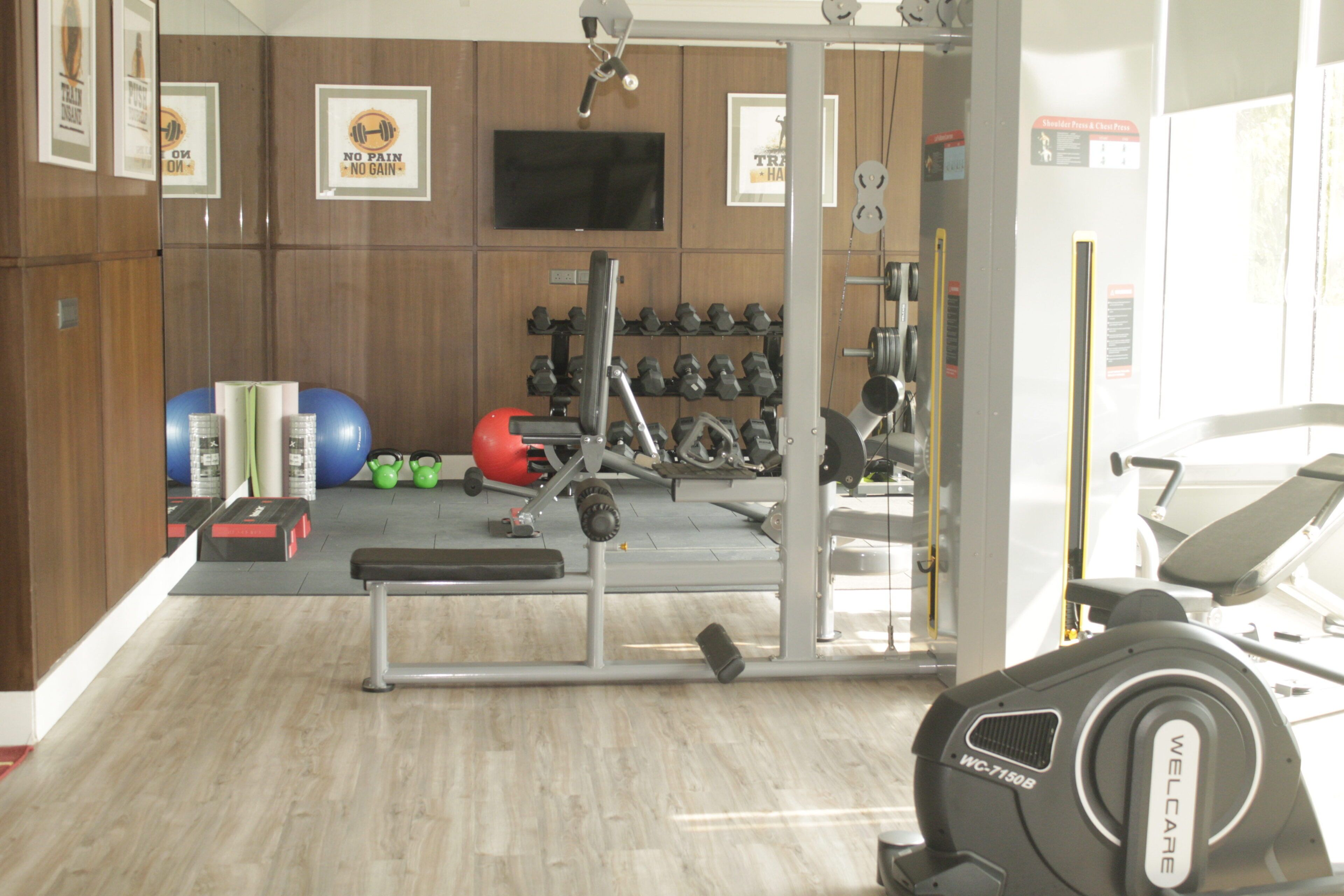 A gym with weightlifting equipment, exercise balls, and a treadmill.
