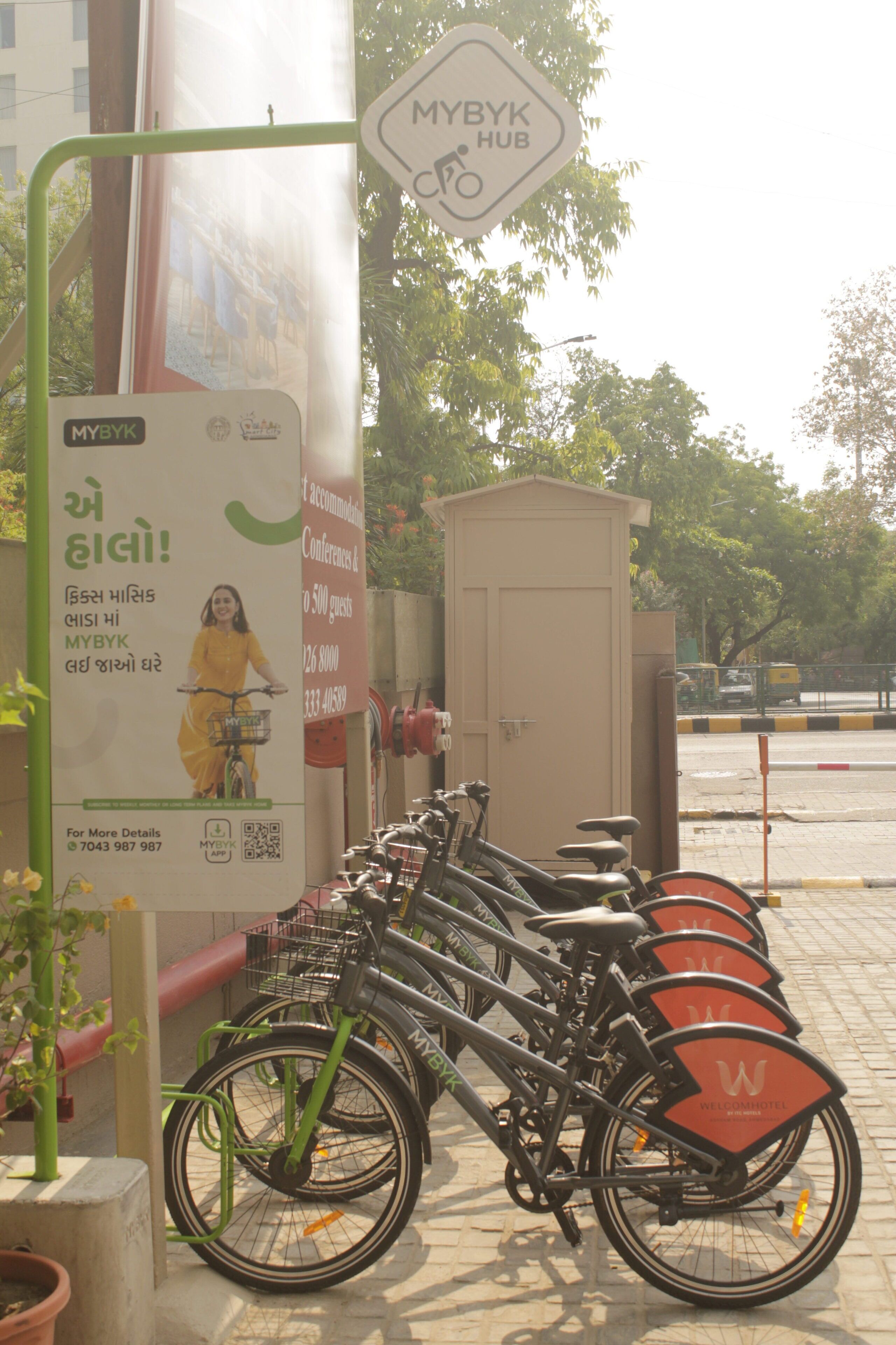 Un panneau indiquant l’emplacement d’un point de service Mybyk, une rangée de vélos et un petit local technique.