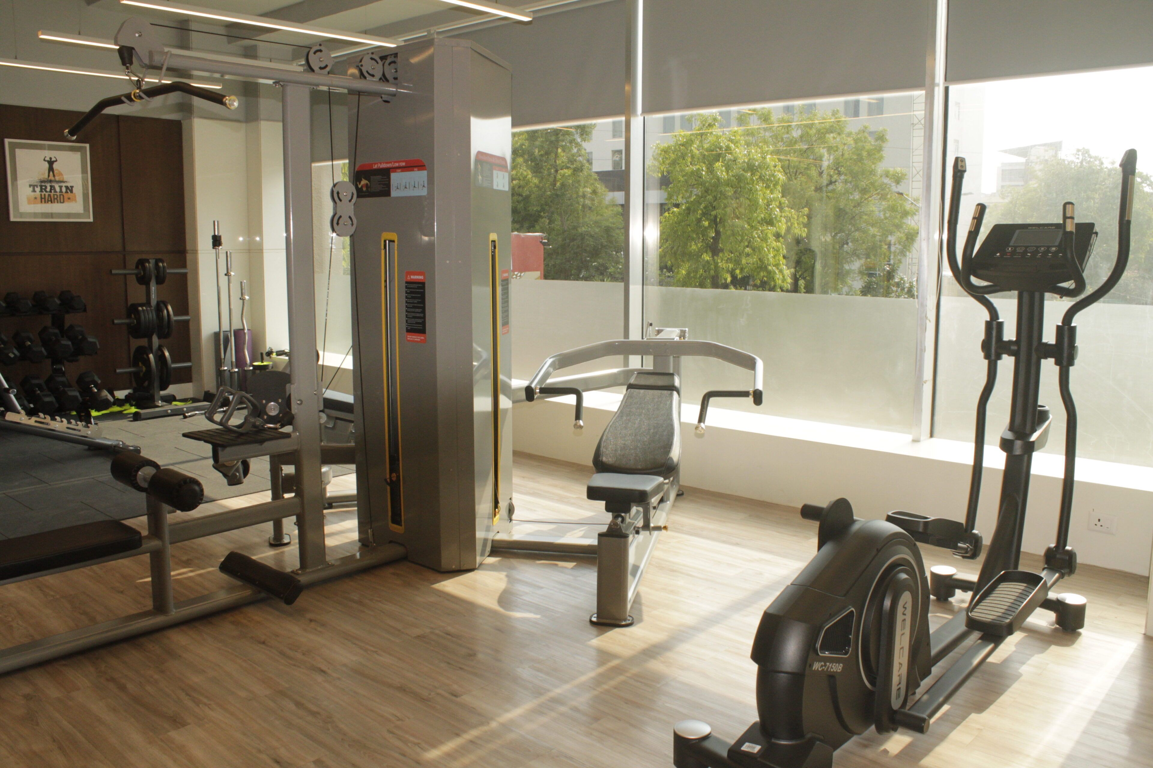 Uma academia com diversos equipamentos de exercícios, incluindo um banco, halteres e máquinas de cardio.