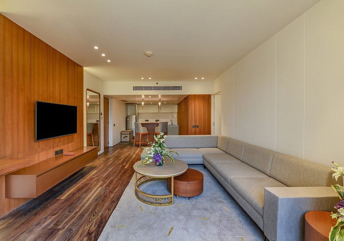 A modern living room with a flat-screen TV, a grey sofa, a round coffee table, and a wooden accent wall.