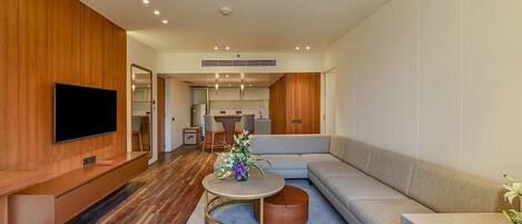 A modern living room with a flat-screen TV, a grey sofa, a round coffee table, and a wooden accent wall.