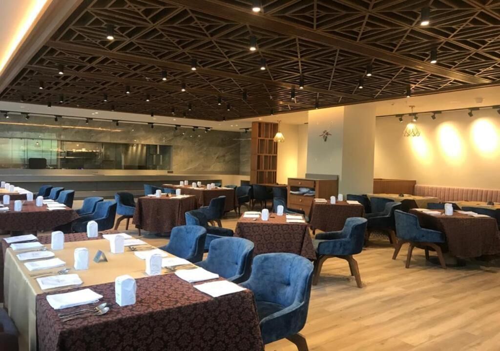 A conference room with round tables, blue chairs, and a wooden ceiling.