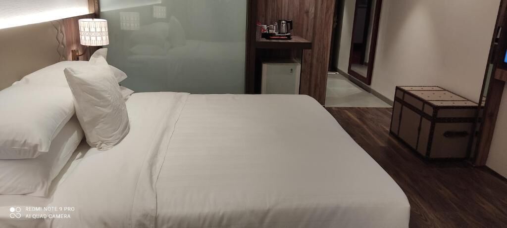 Una cama bien hecha con sábanas blancas en una habitación de hotel.