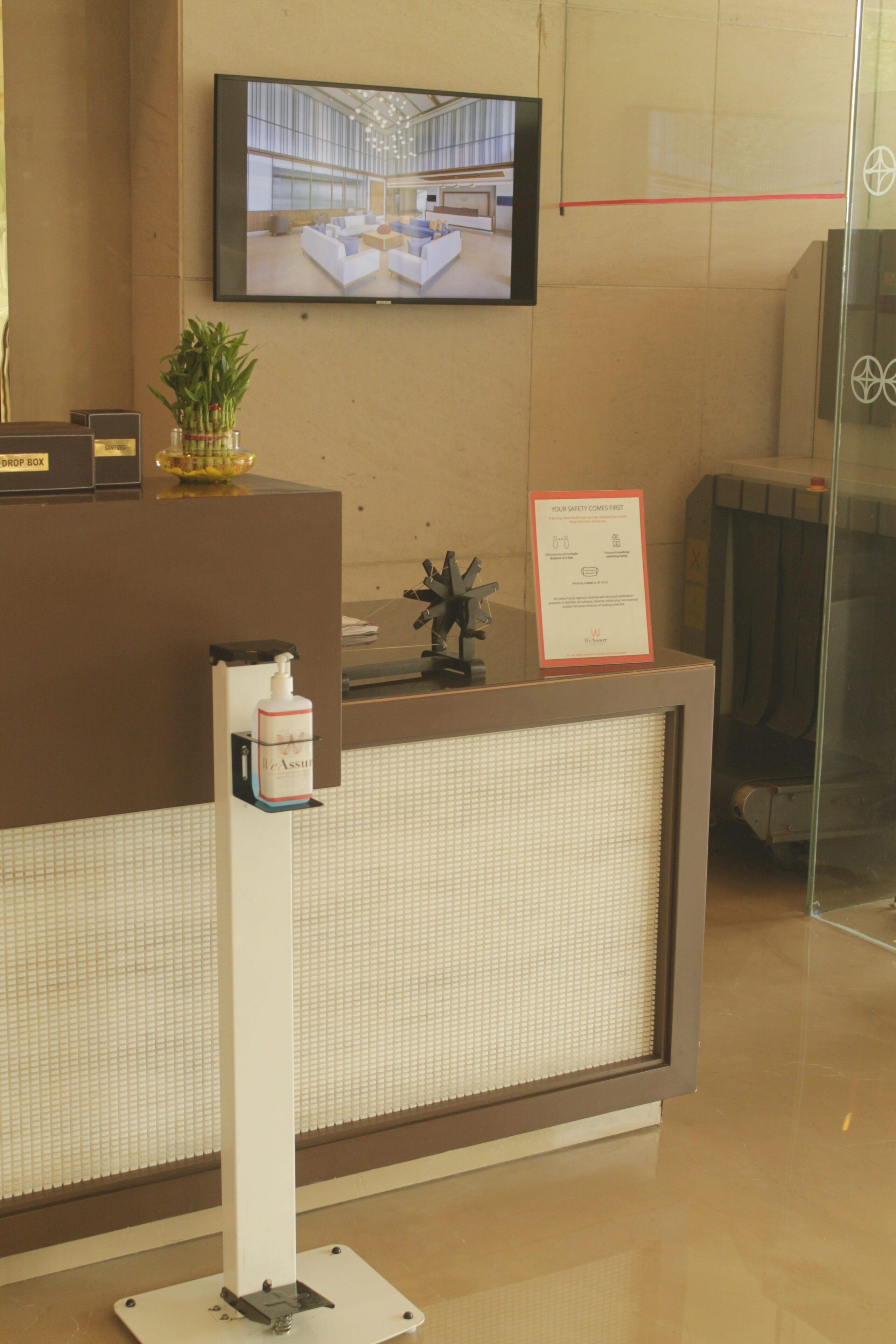 A reception desk with a television displaying a lobby view, a drop box, and a safety notice.
