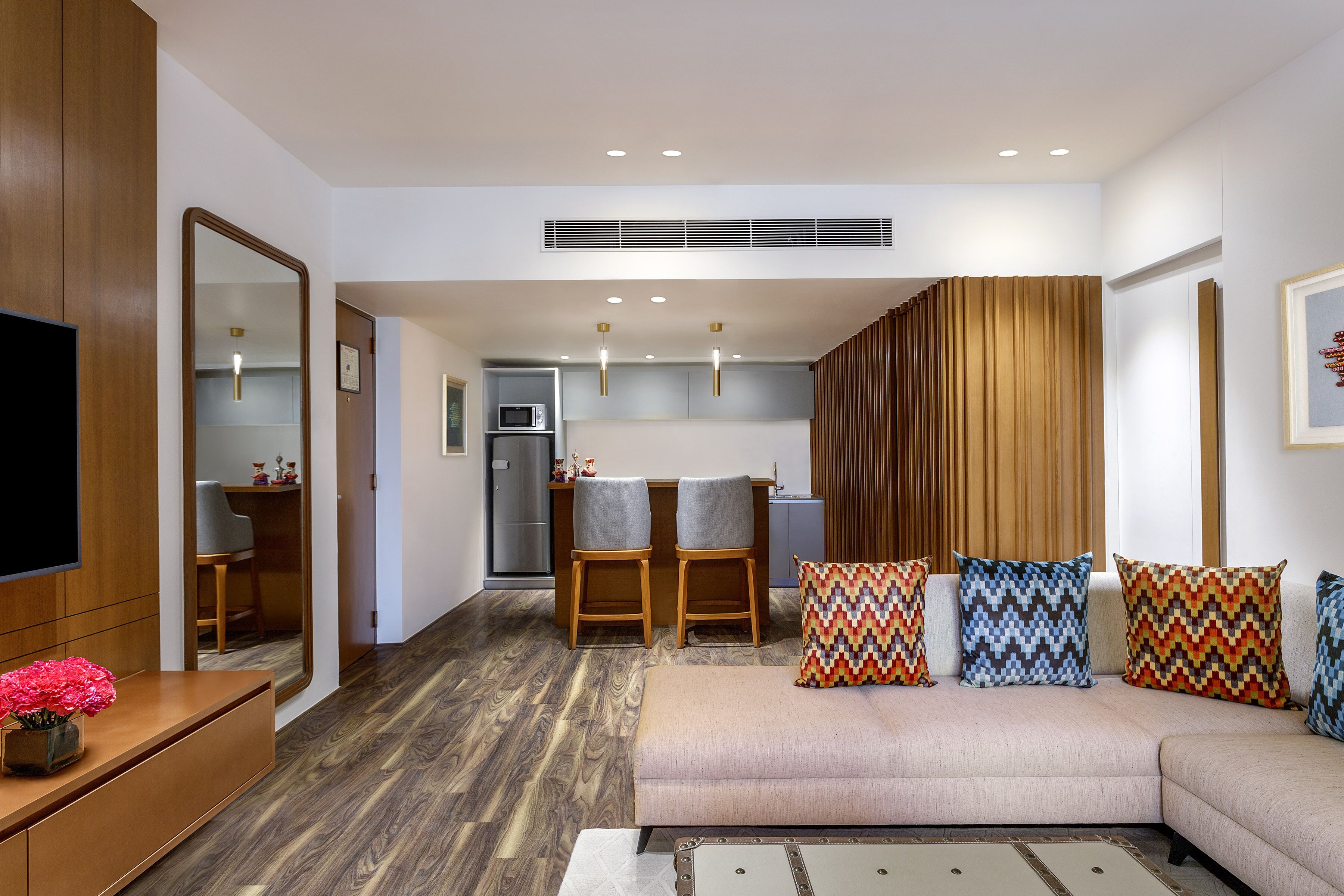 A modern living room with a sofa, a TV, and a dining area with chairs and a table.