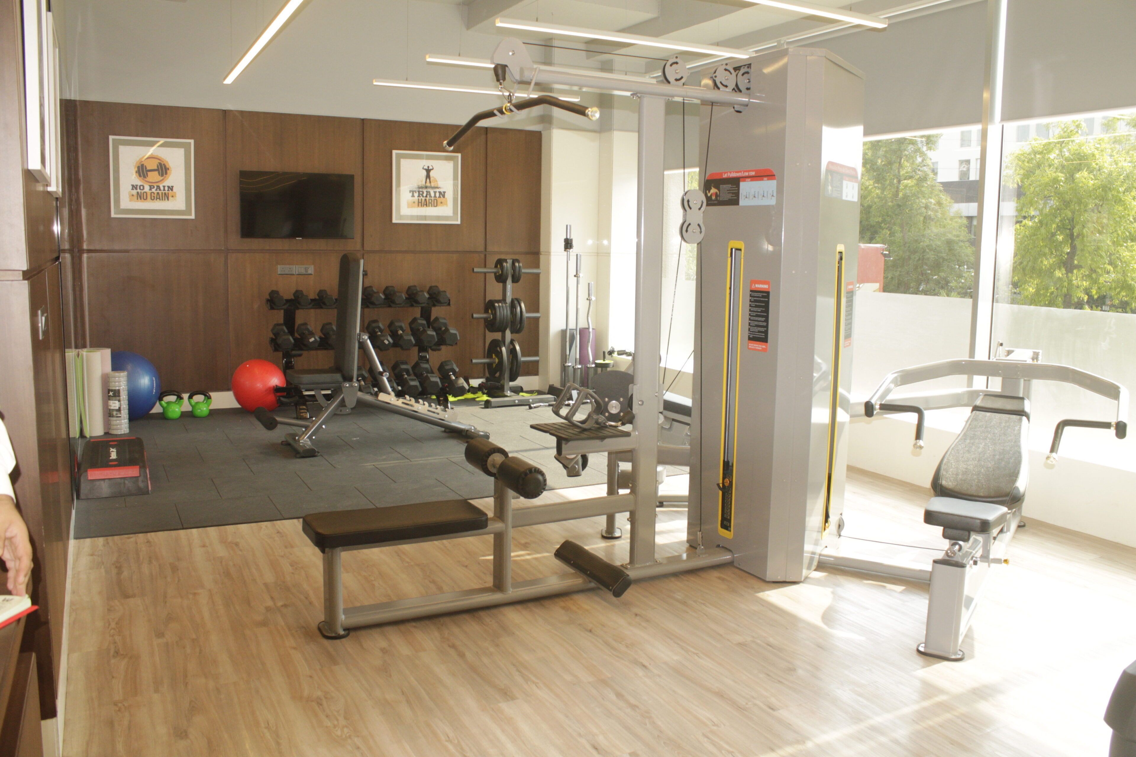 A gym with weightlifting equipment, exercise balls, and a bench.