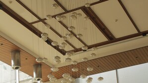 Un intérieur moderne avec un plafond haut, des luminaires sphériques suspendus et un canapé bleu agrémenté de coussins à motifs.