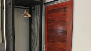 Ένα δωμάτιο με μια ξύλινη ντουλάπα, μια κρεμάστρα και ένα μικρό ράφι με διπλωμένες πετσέτες.